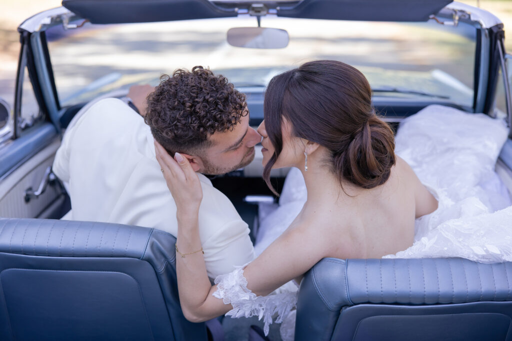 Bride and groom portraits in a convertible baby blue Mustang.
