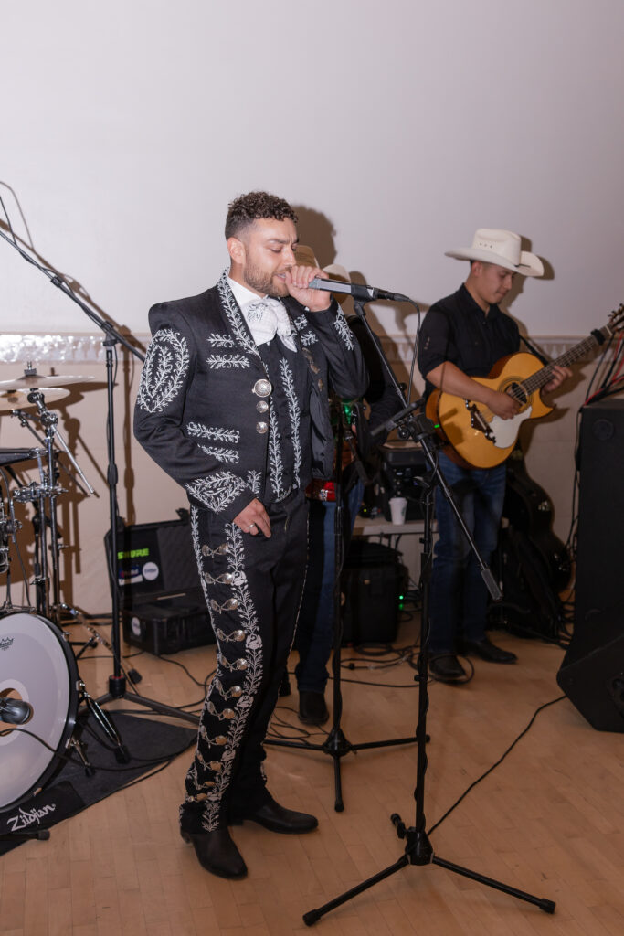 Groom wearing traditional Mexican wedding attire singing to his bride at their Grand Gimeno wedding reception.
