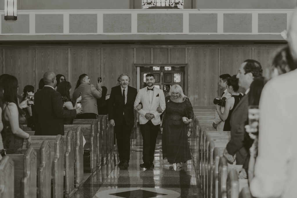 Groom walking down the aisle with his parents at the Saint Emydius church in Los Angeles.
