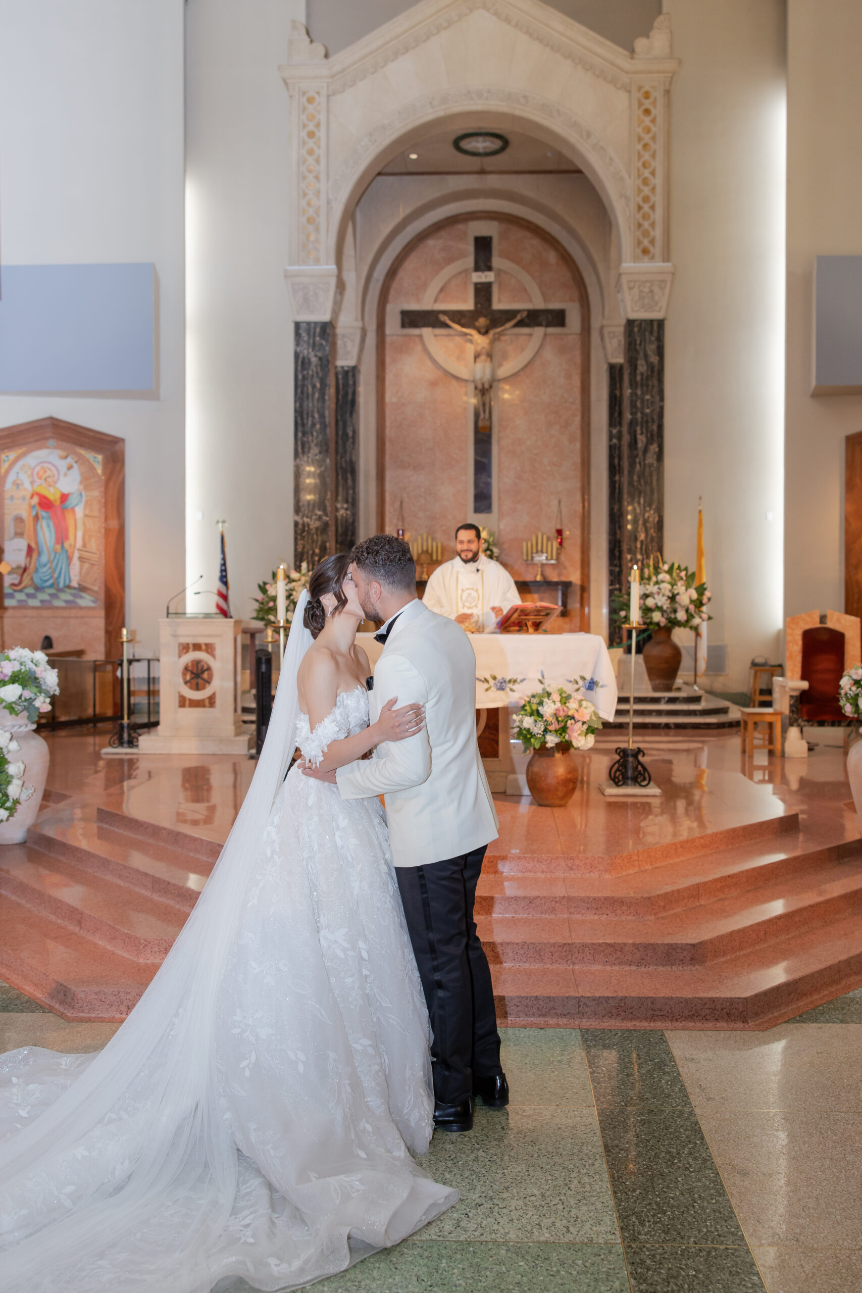 Bride and groom kissing at the altar at Saint Emydius church in Los Angeles.