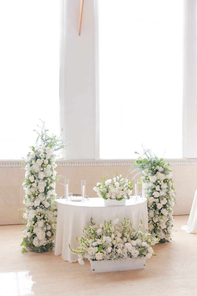 Romantic and elegant bride and groom sweetheart table at Grand Gimeno with freestanding floral arch arrangements.