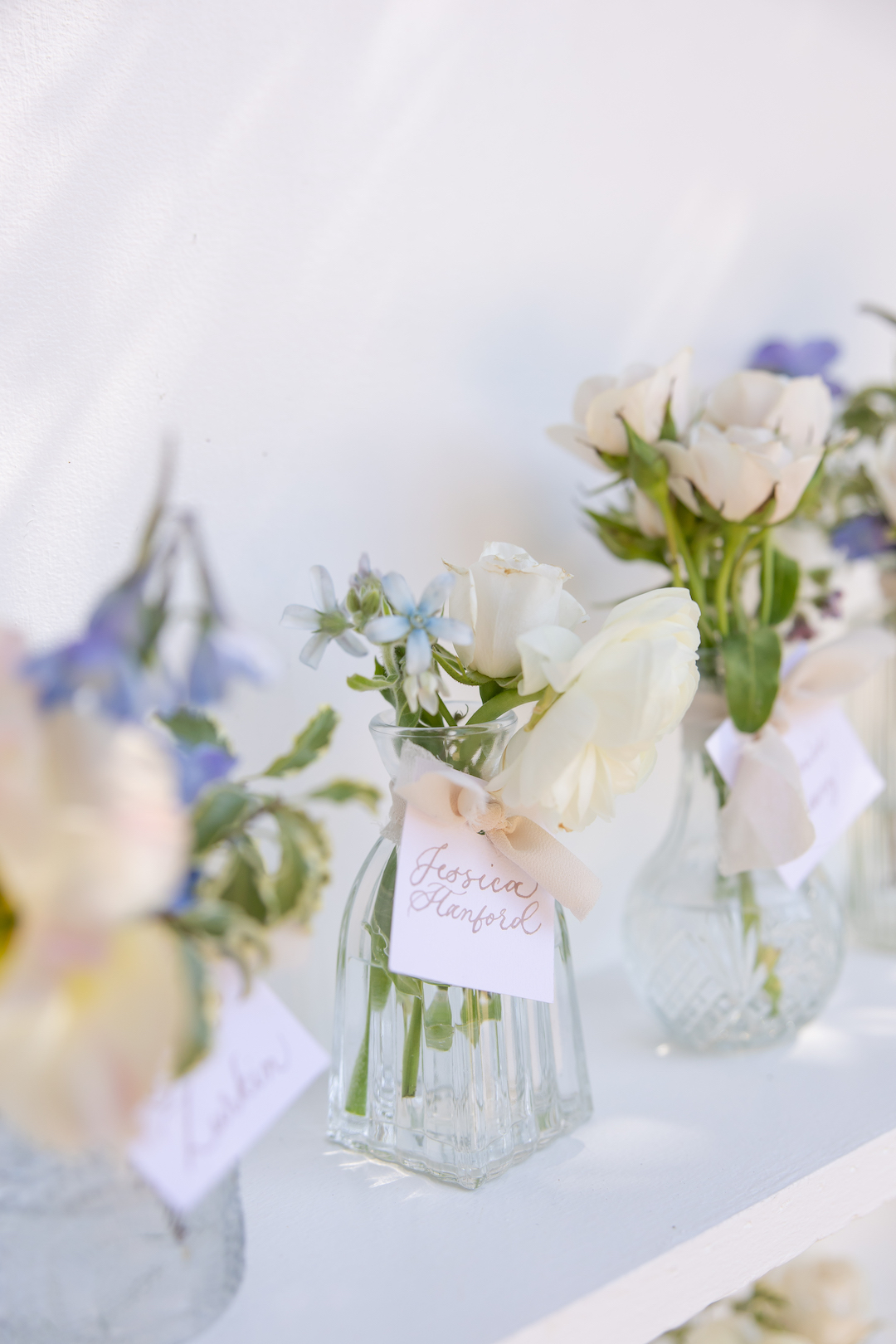Whimsical floral arrangements delicately placed in an array of bud vases. 