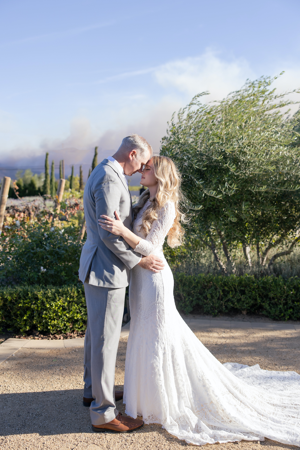 Bride and groom touching noses posing in front of lush gardens at Tuscan Rose Ranch. 