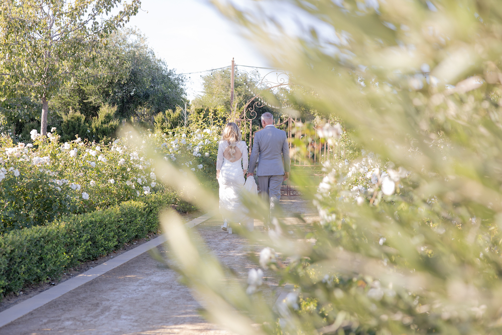 Bride and groom walking towards the gates of their garden wedding venue Tuscan Rose Ranch.