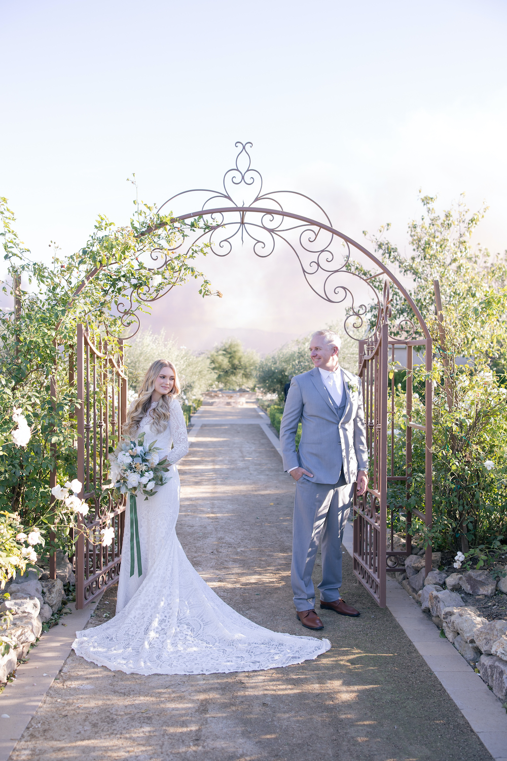 Bride and groom posing at the gate of Tuscan Rose Ranch. 
