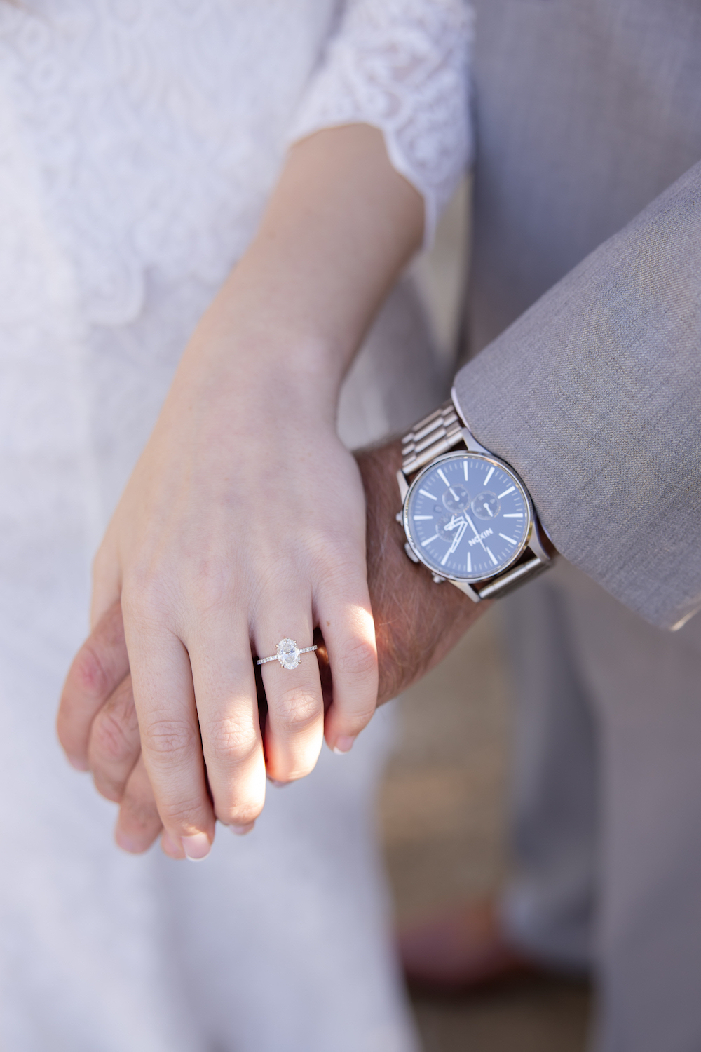 Up close detail shot of the bride's engagement ring and the groom's watch. 