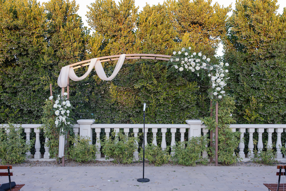 Tuscan Rose Ranch wedding ceremony altar with a floral and drapery adorned arch. 