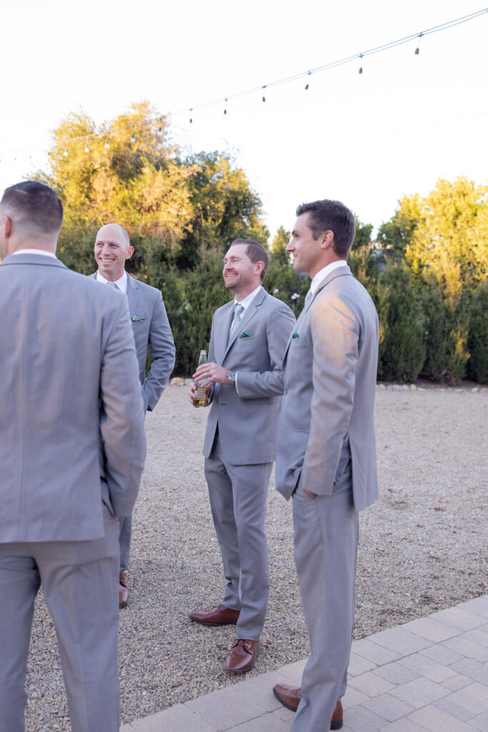 Groomsmen in candid conversation pre-ceremony at Tuscan Rose Ranch. 