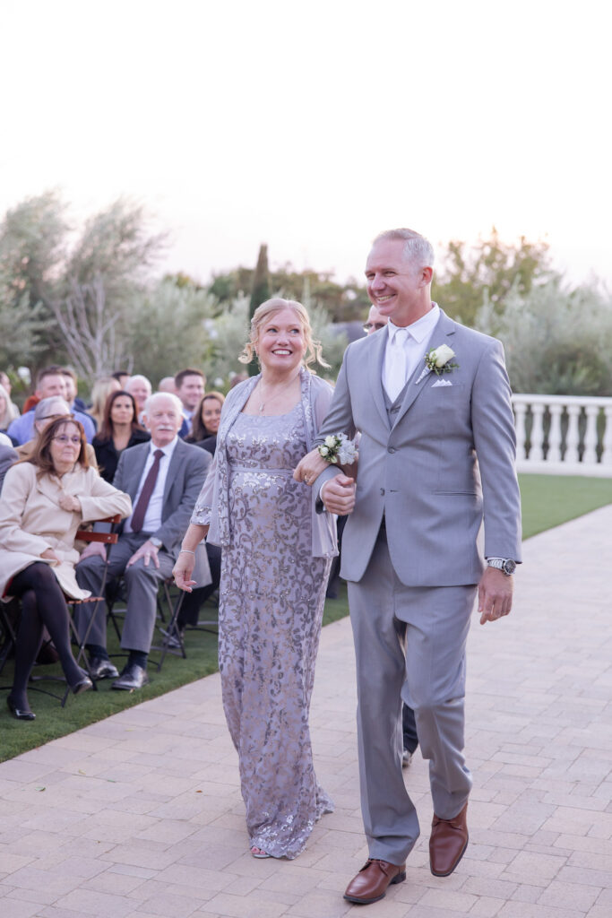 Groom walking down the aisle with his mother at Tuscan Rose Ranch. 