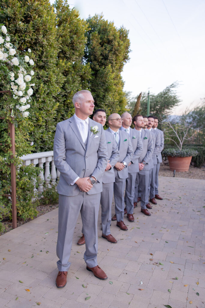 Groom and groomsmen at the altar watching the bride walk down the aisle at Tuscan Rose Ranch.