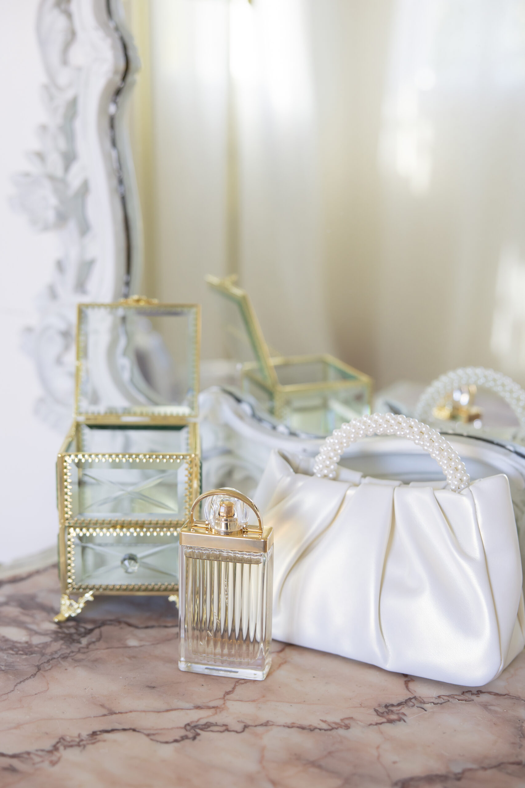 Romantic and elegant bridal details with a white purse, perfume and jewelry box. 