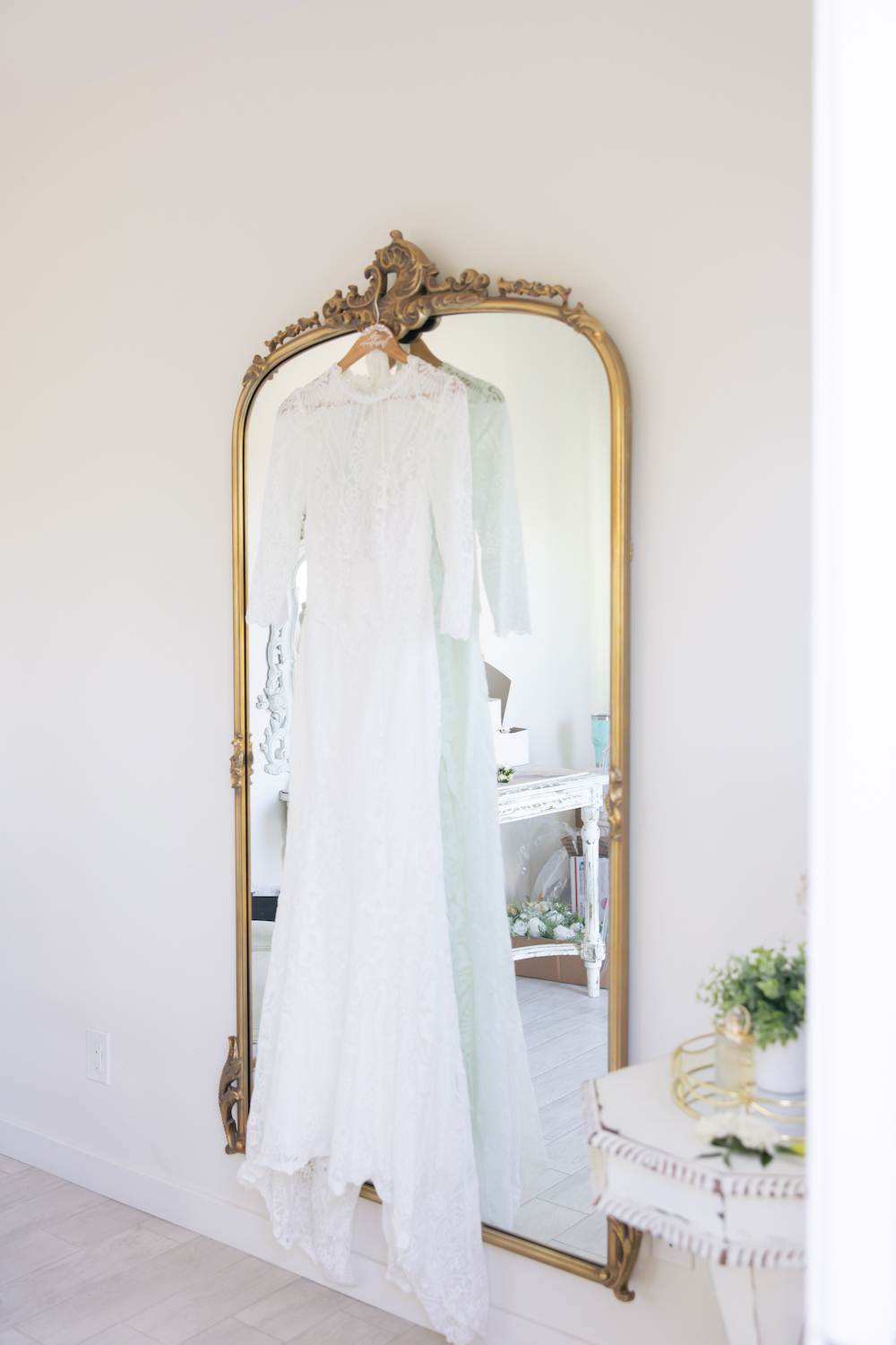 Wedding dress hanging from a vintage gold mirror at Tuscan Rose Ranch.