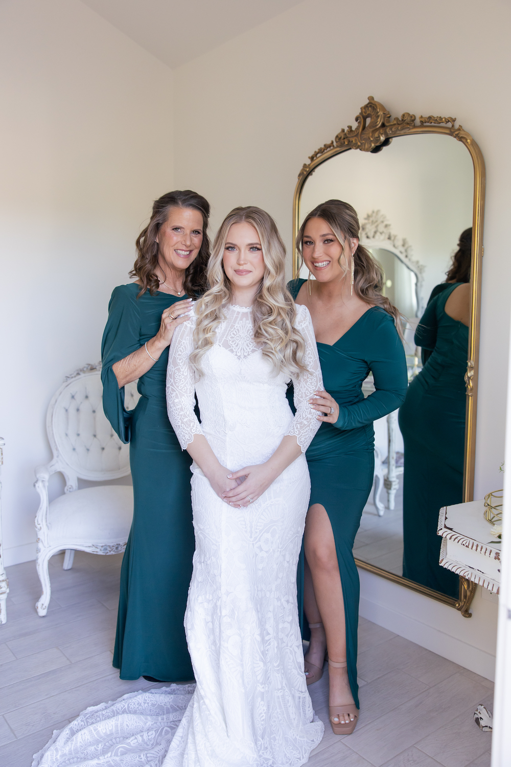 Bride posing with her mom and sister in the Tuscan Rose Ranch bridal suite. 